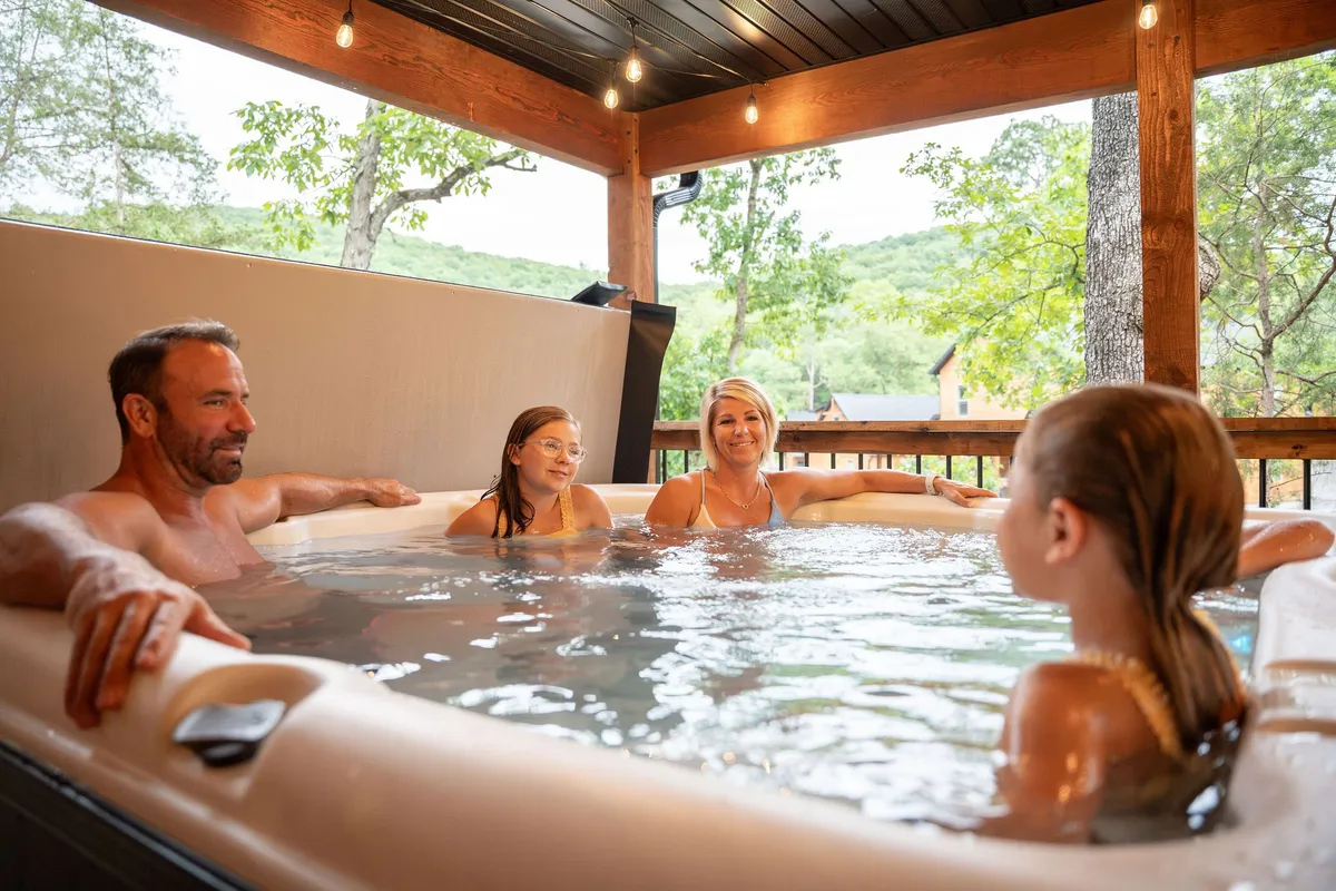 A private hot tub set on a deck, surrounded by natural greenery, with family members relaxing and enjoying the peaceful setting. The scene captures the hot tub overlooking tranquil nature, embodying relaxation and togetherness.